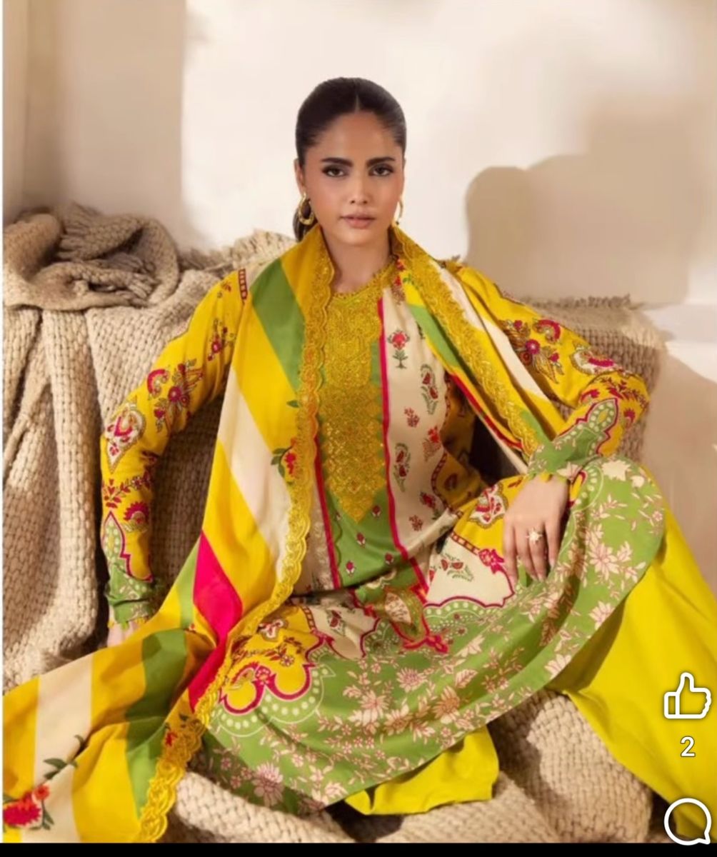 Model seated in a mustard yellow embroidered suit